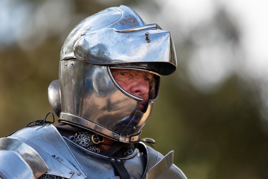 A man in a tight-fitting shiny mediaeval helmet for jousting.