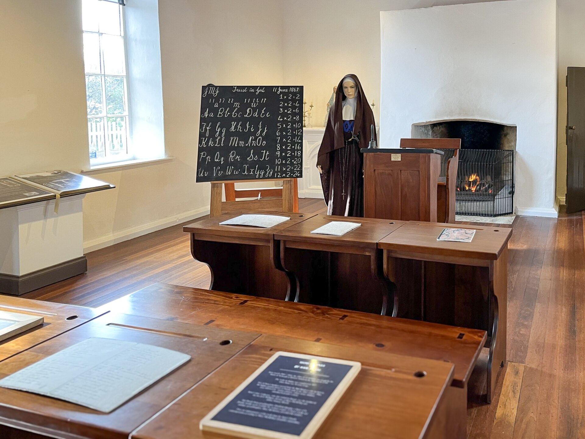 A mock-up of an old schoolroom in an old building with a nun mannequin