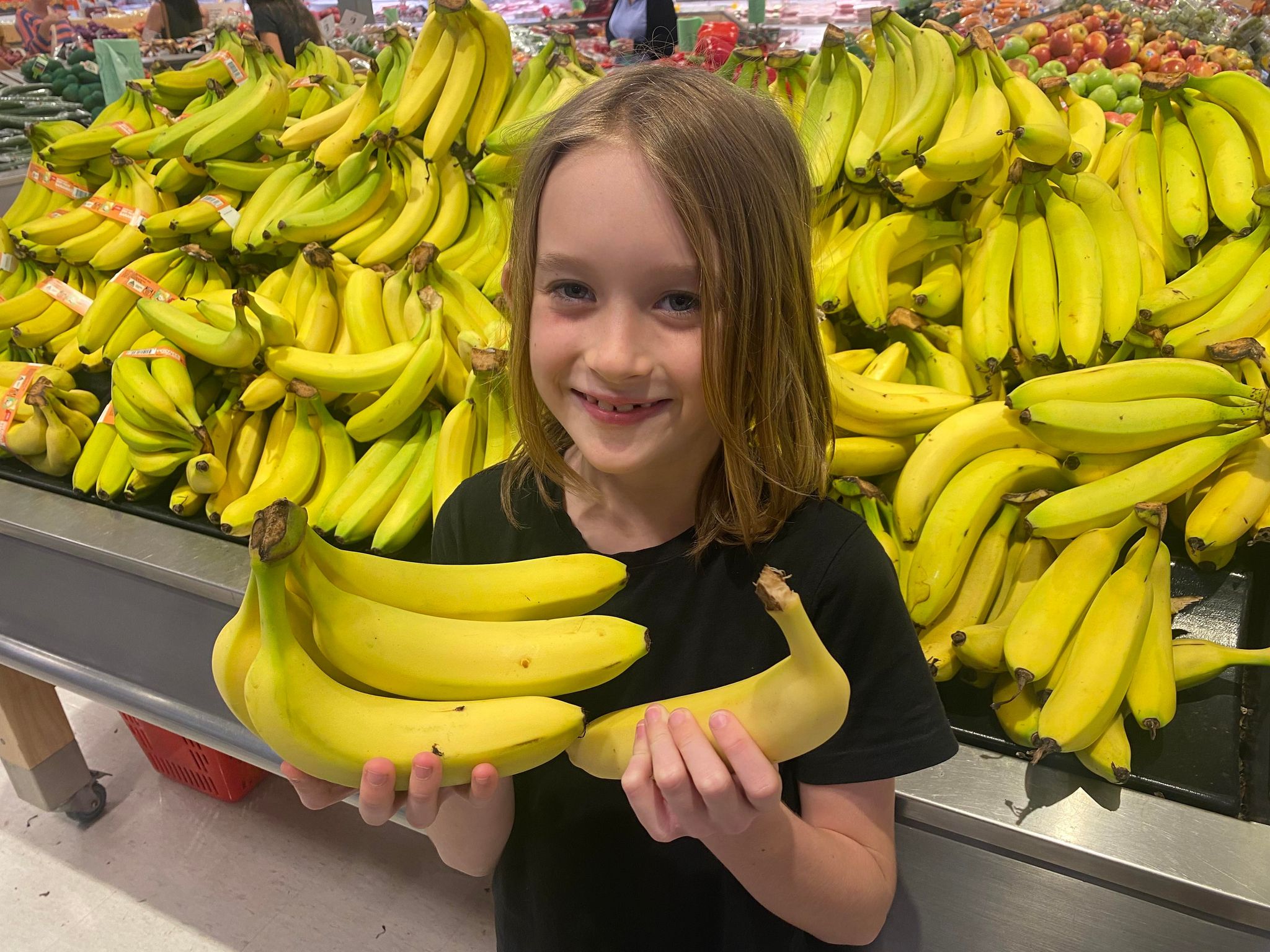 Travis Stewart stands in front of bananas at the supermarket holding bananas in both hands
