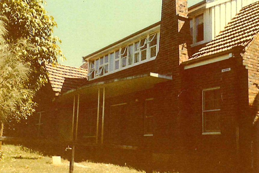 An old photograph of a brick building with a bank of windows on the second floor.