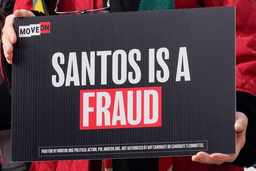 The black, white and red sign says: Santos is a fraud.