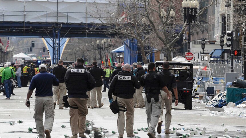 Carnage ... officials evacuate the explosion scene in Boston.