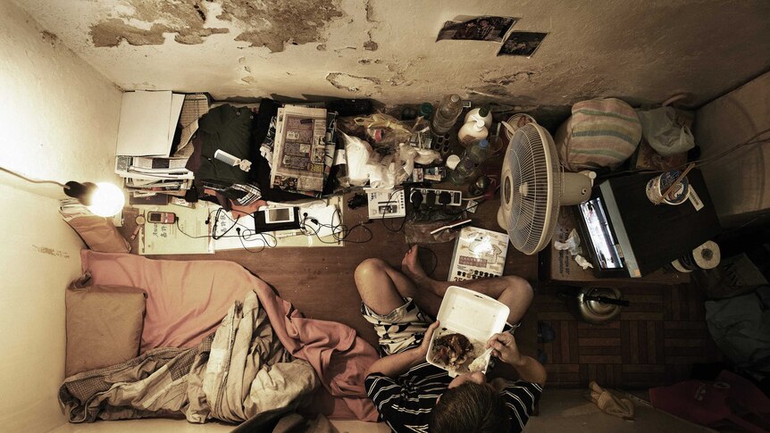 A man eats in a tiny flat in Hong Kong.