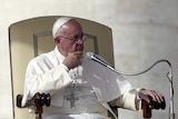 Pope Francis sitting on a chair.