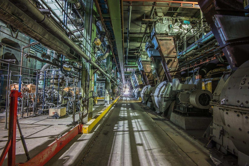 The inside of a coal power plant with coal pulverisers and other machinery lining the walls.