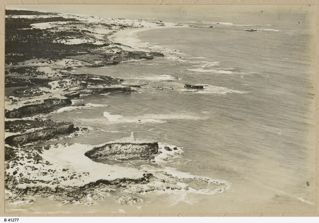A black and white photo of a rocky coast line with large waves crashing into rocks