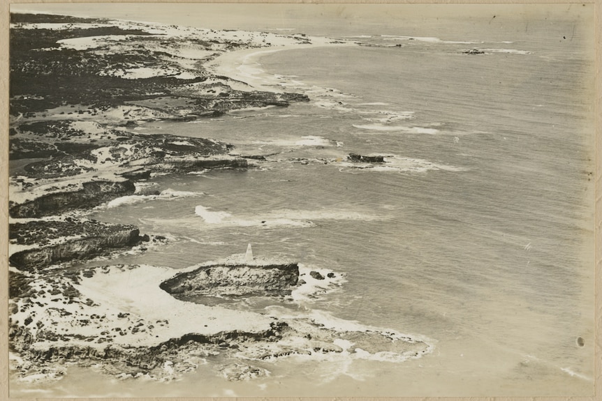 A black and white photo of a rocky coast line with large waves crashing into rocks