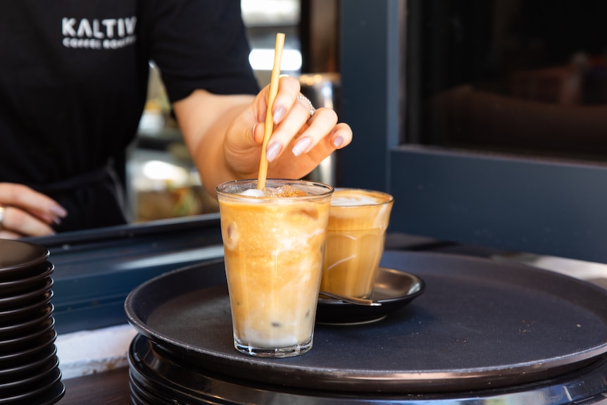 A paper straw being put into a coffee.