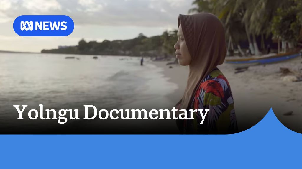 Yolngu Documentary: A woman with a brown headscarf standing on a beach looking out at the sea.