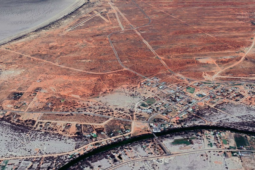 A satellite image of a small town surrounded by a red and grey expanse of land.