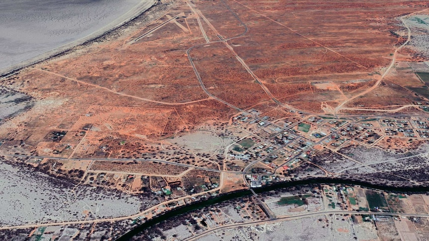 A satellite image of a small town surrounded by a red and grey expanse of land.