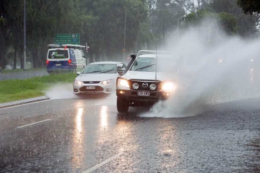 Cars are seen driving through heavy flood waters in Moorooka, Brisbane.