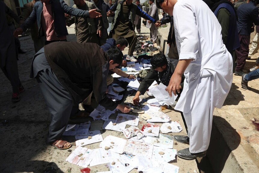 People are seen searching through papers smeared by blood.