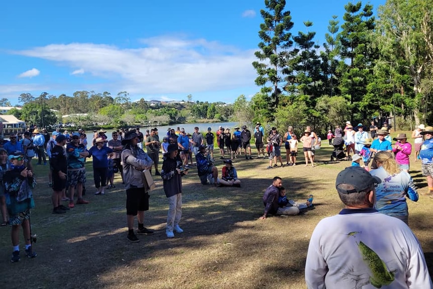 Lots of people gathered near a lake.