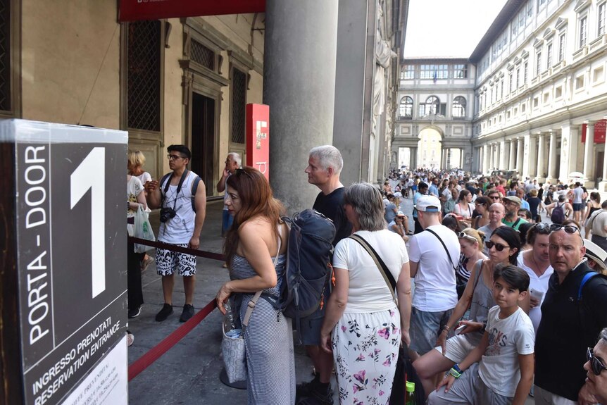 A large crowd of tourists queueing to enter the Uffizi Gallery in Florence.
