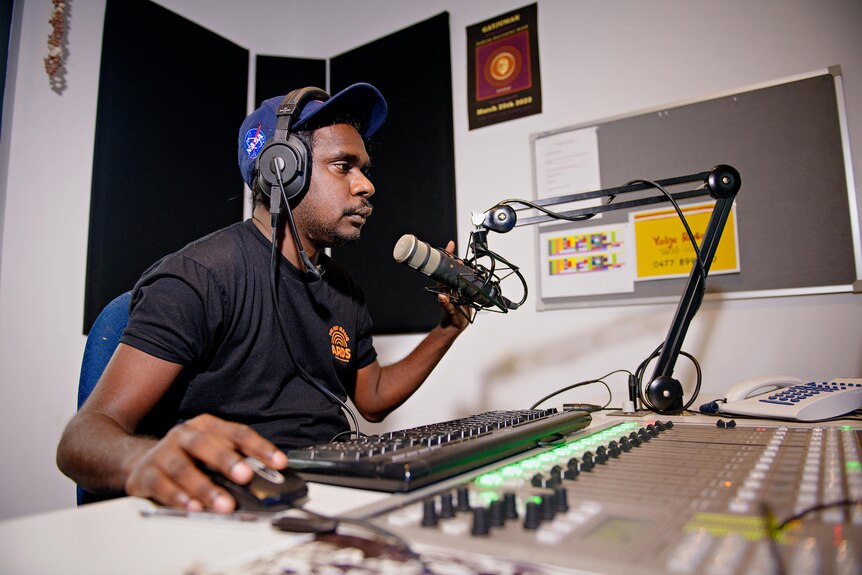 William Mungul Gumbula works at a computer inside a radio production booth.