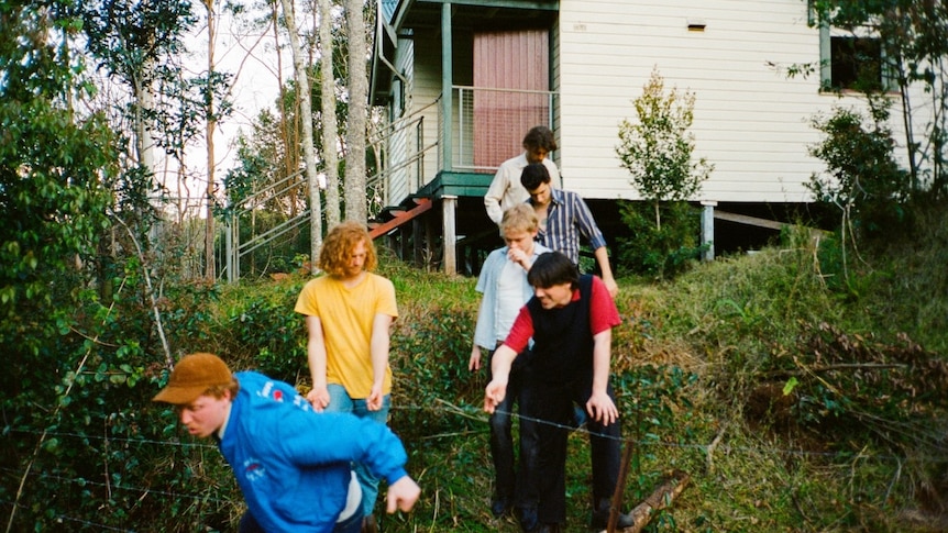 Six men walk down a hill with lots of trees around them