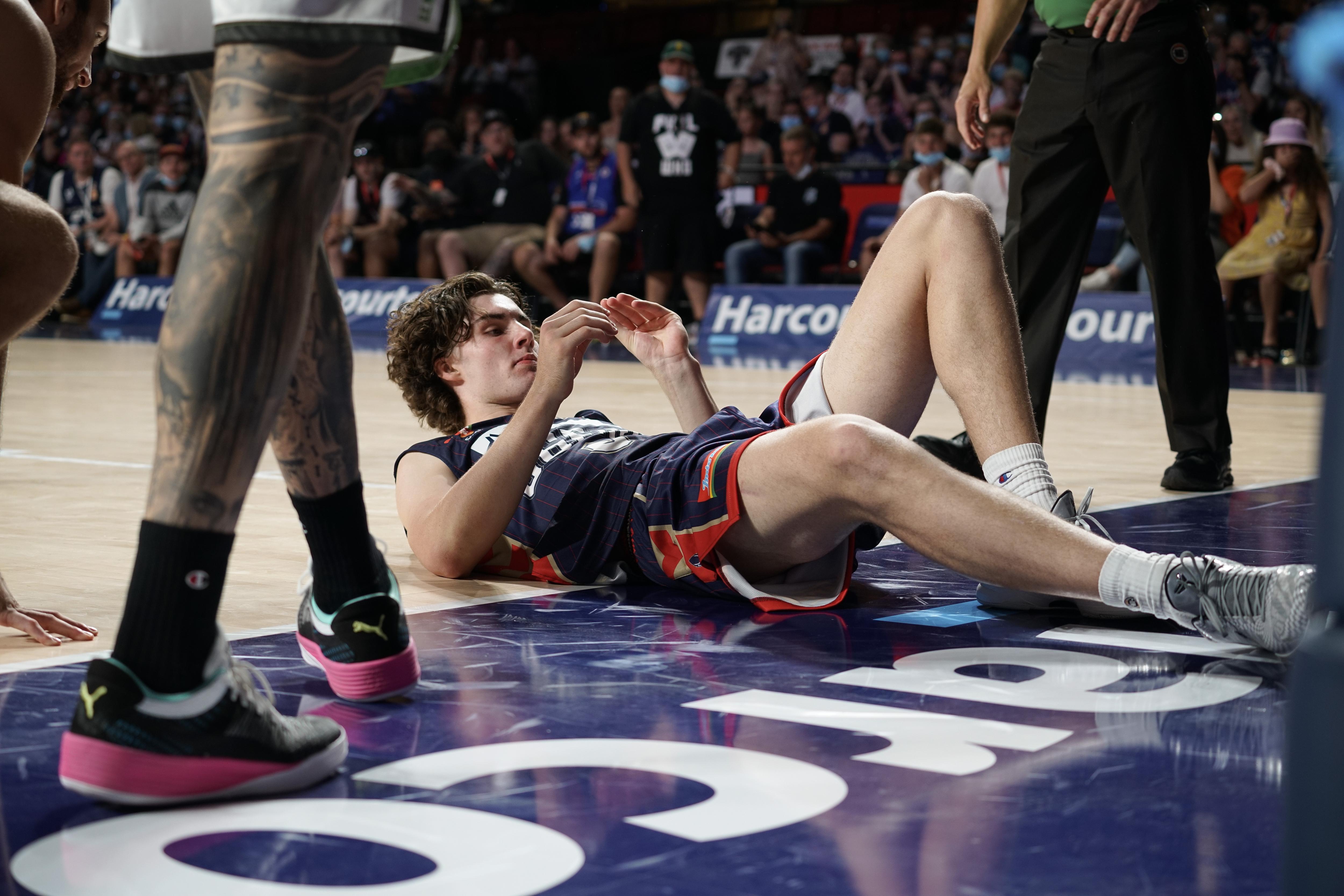 Josh Giddey lays on the court after being knocked over in a contest