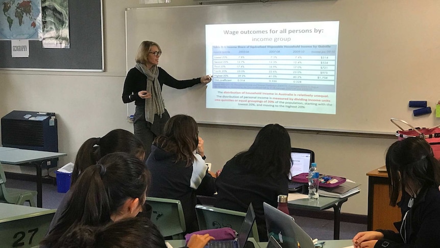 A teacher stands in front of a classroom of students