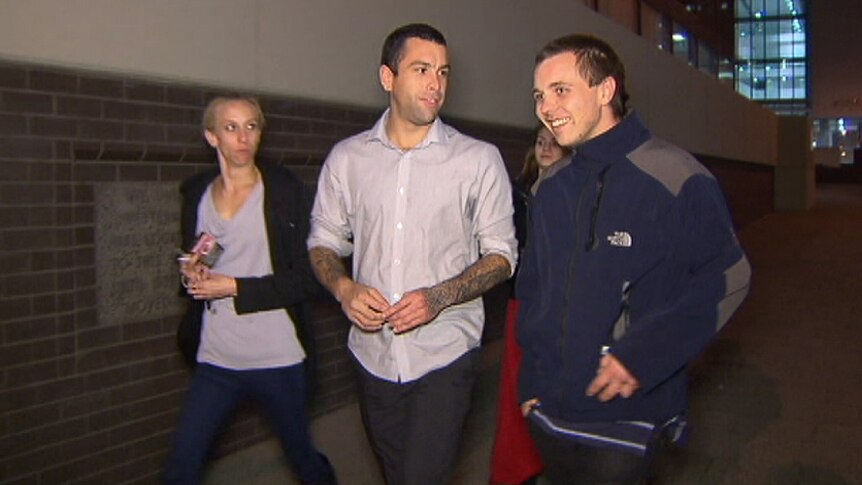 Hayden Joseph and Damien Mathews walk along a footpath at night with a woman by their side and another behind them.