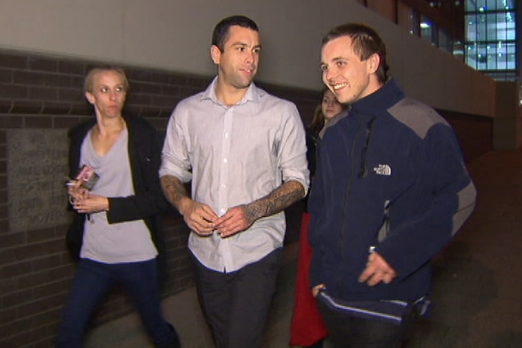 Hayden Joseph and Damien Mathews walk along a footpath at night with a woman by their side and another behind them.