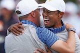 Tiger Woods screams in delight as he hugs Justin Thomas.