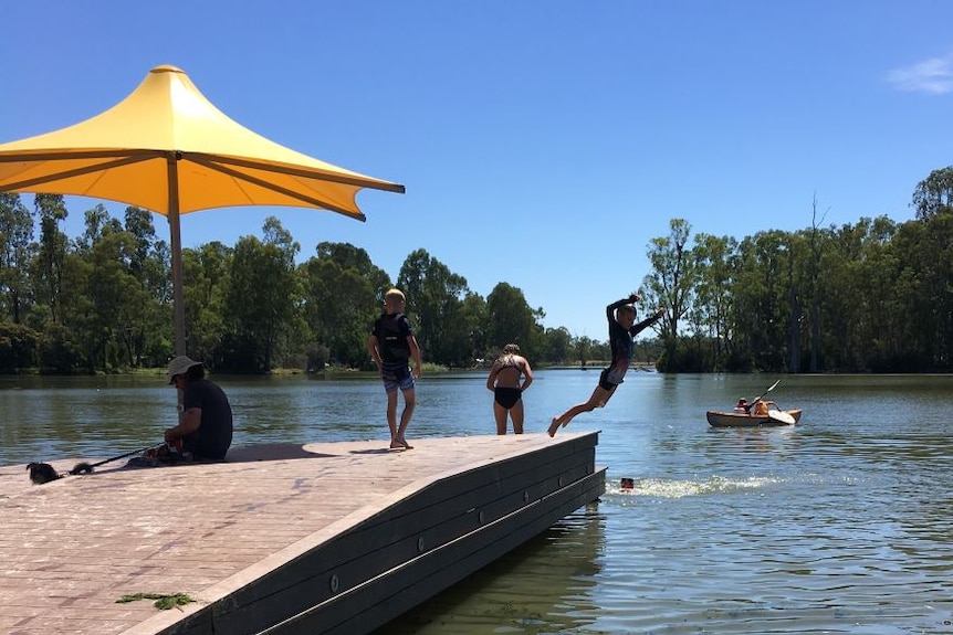 A boy jumps from the jetty at Cohuna beach and into the Gunbower Creek