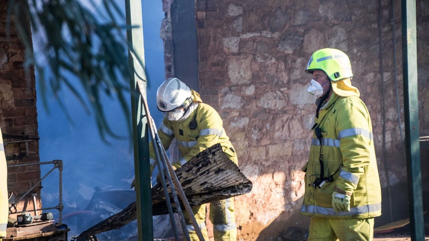Firefighters clearing debris after extinguishing a fire at an outback pub.