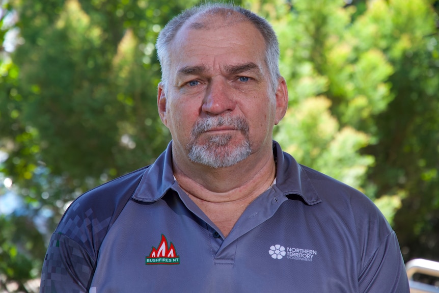 A man in his 50s looks at the camera, with a serious expression. He is wearing a branded Bushfires NT polo shirt.