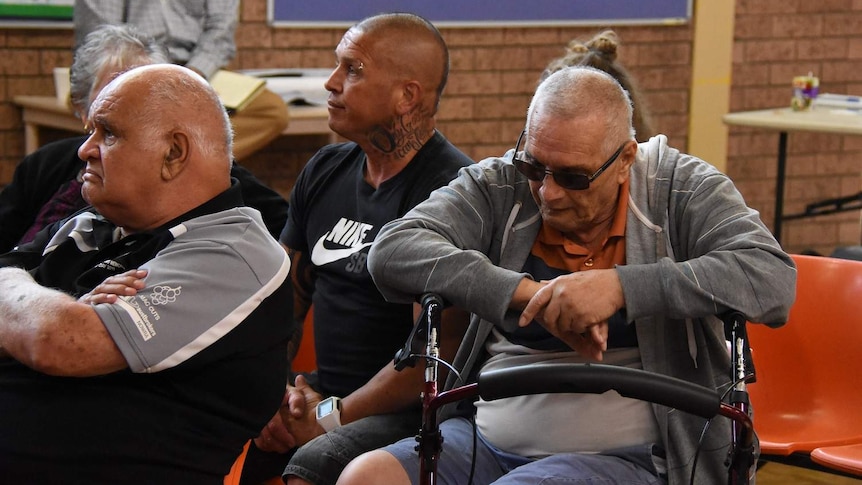 Three men at a public meeting