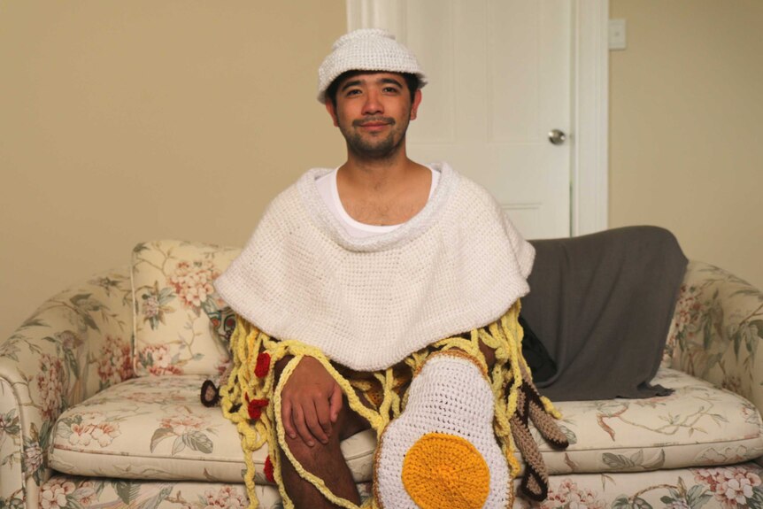 A young man in a crochet ramen noodle outfit.