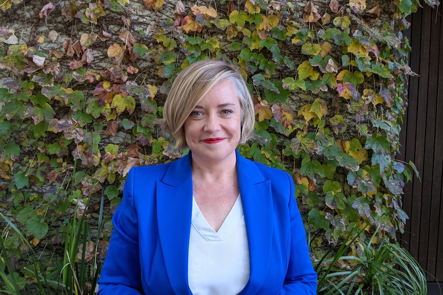 Une femme souriante tout en portant une veste bleue