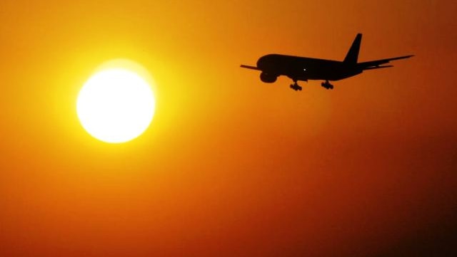 A planes flies at sunset.