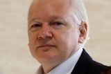 A close-up photo of Julian Assange's face as he walks into court in a suit.