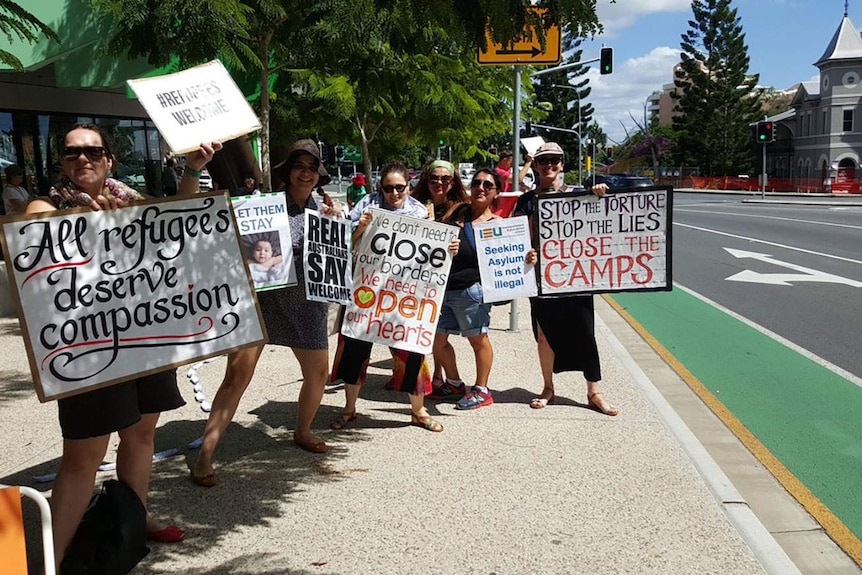 Protesters hold placards on the roadside near Lady Cilento Children's Hospital