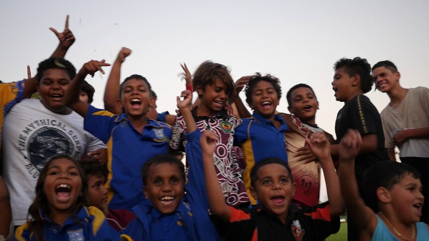 Un grupo de niños sonríe y celebra a la cámara. 