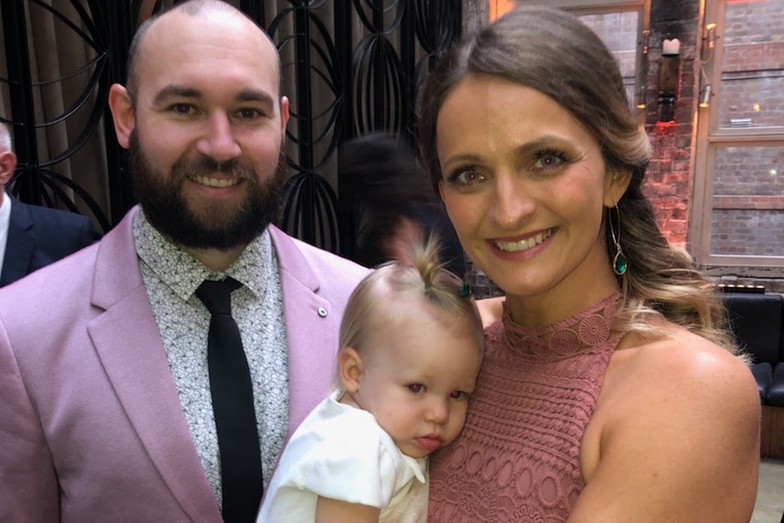 Emma Elder, right, holds baby Claire as she stands next to partner Michael, left.