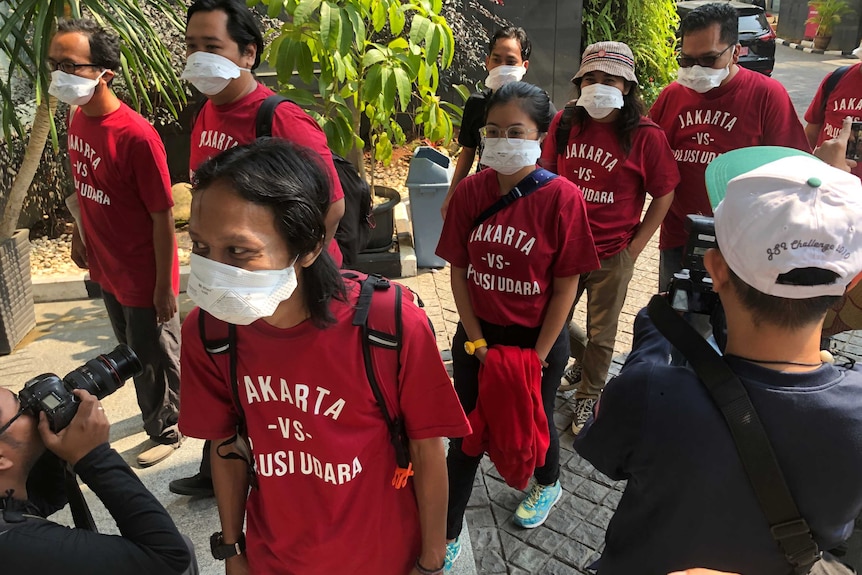 People in red t-shirts and face masks file into a court room