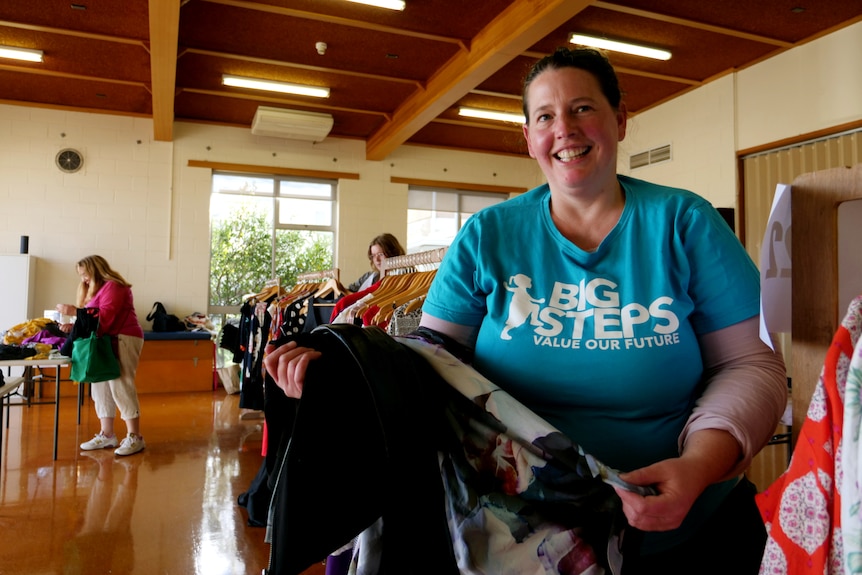 Photograph of a large smiling white woman with a pile of clothes in her arms