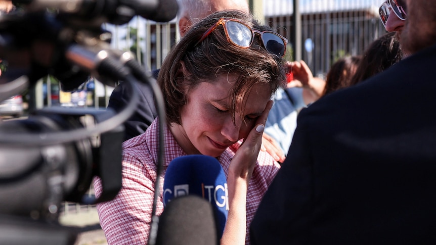 A woman surrounded by cameras, crying. 