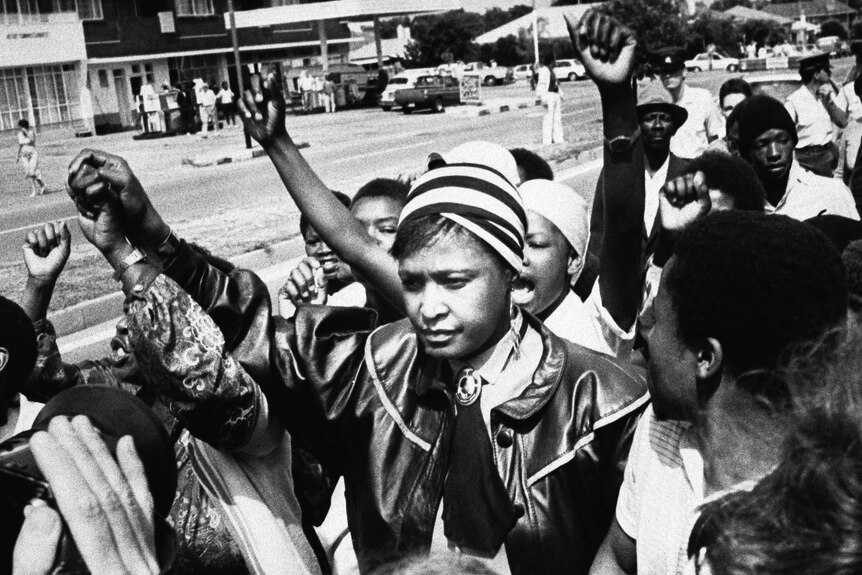 Winnie Mandela is cheered by supporters in 1986 in a black and white photo.