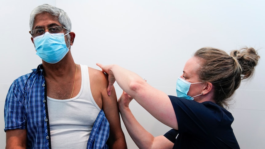 A healthcare worker gives a man a coronavirus vaccination