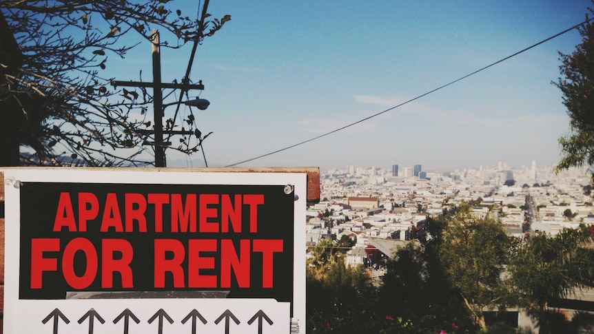 A sign reading 'For Rent' overlooks a big city.