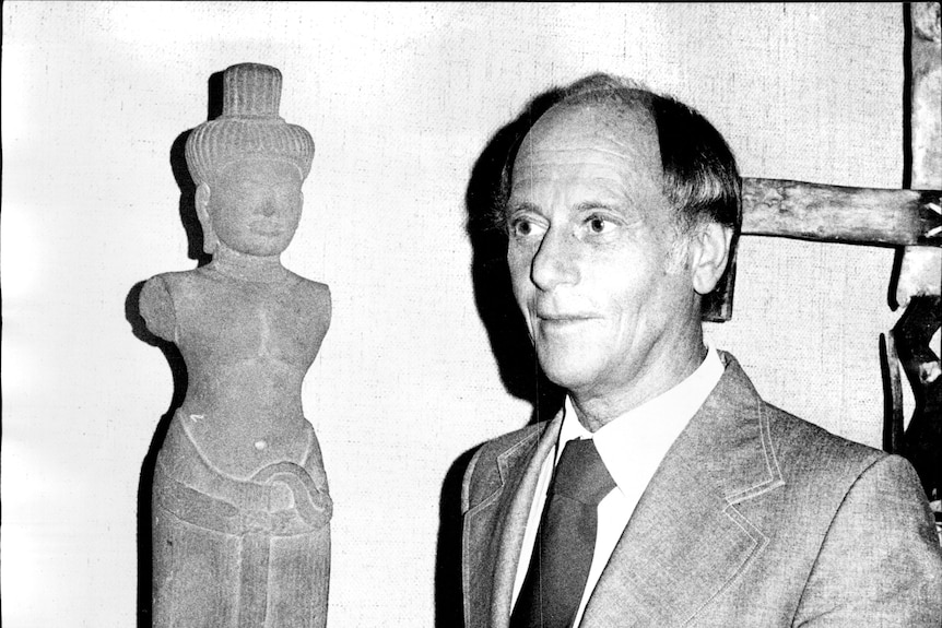 B&W photo of man in suit holding a sculpture