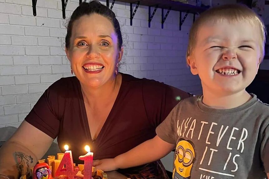 A woman with a cake next to a little boy