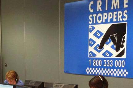 People sitting in a call centre office with a crime stoppers banner in the background