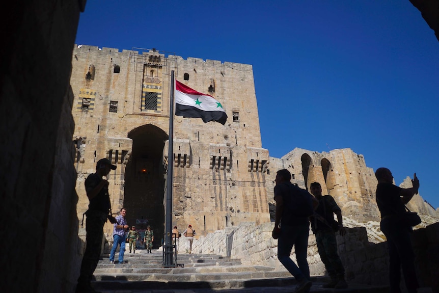 Visitors and Russian military police officers walk toward the Citadel, Aleppo's famed fortress