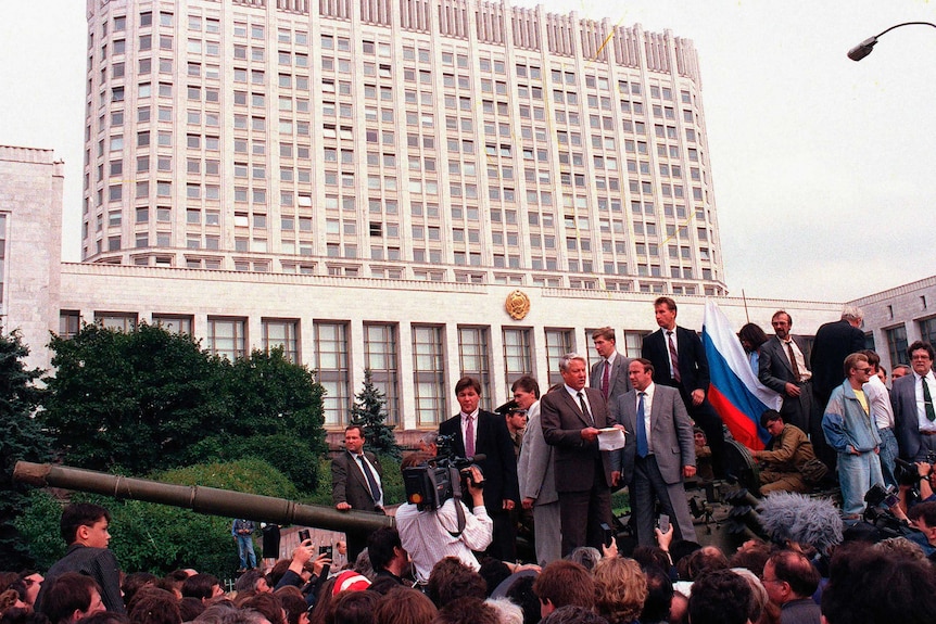 Boris Yeltsin stands atop a tank with other soviet bureaucrats reading from paper