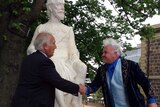 Frank Costa and Darryn Lyons shake hands in front of restored statue