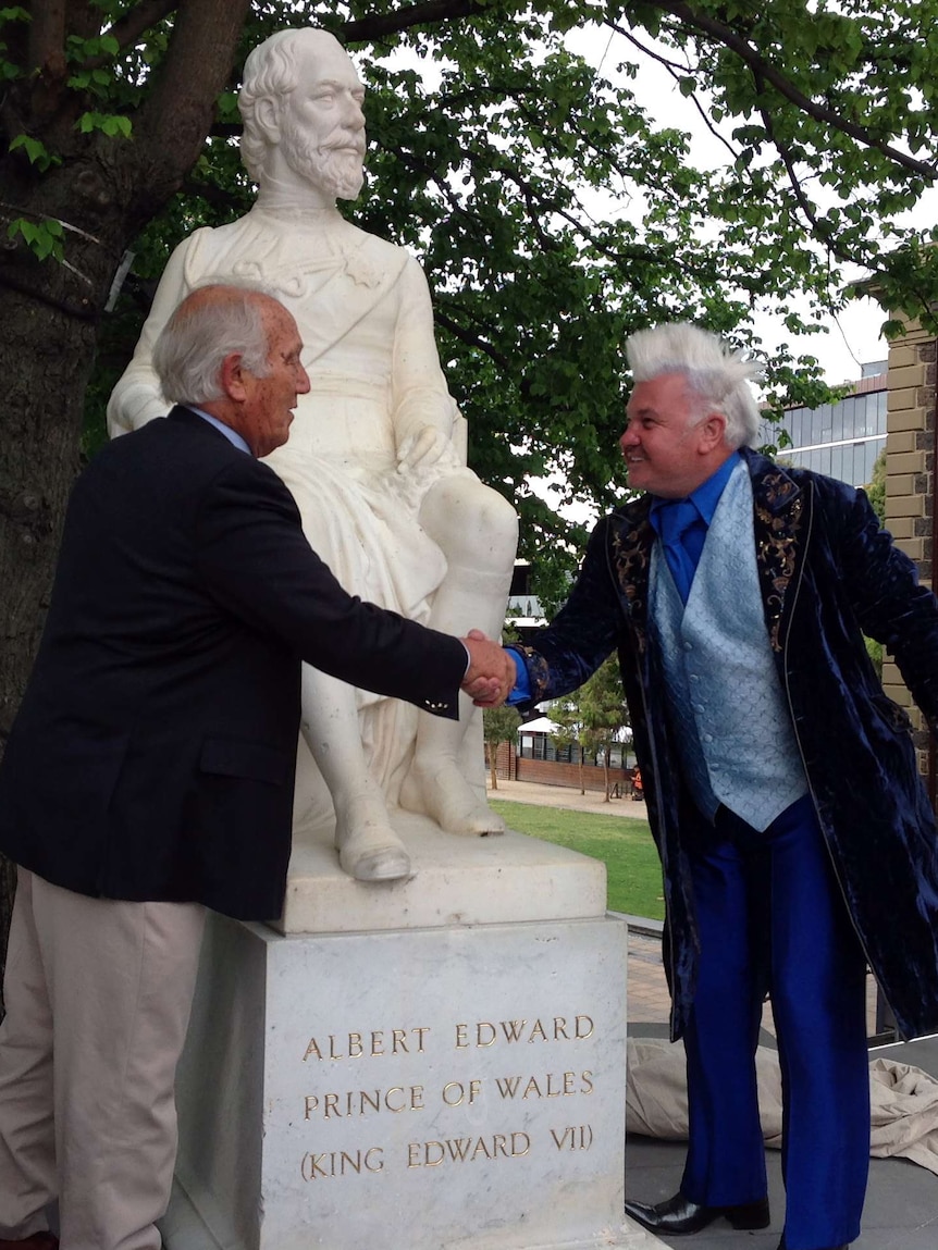 Frank Costa and Darryn Lyons shake hands in front of restored statue
